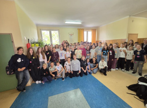 Uczniowie klas 4 – 8 na korytarzu szkolnym prezentują swoje ubrania w kropki.