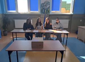 Uczennice klasy 8 a siedzą przy stolikach w Sali 16 w komisji do wyborów na Przewodniczącą Szkoły.