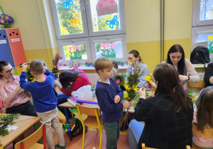 Staś pomaga mamie w wykonaniu pięknej palmy z zużyciem kwiatów z bibuły, bukszpanu i gałązek wierzbowych.