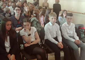 grupa uczniów i opiekunów w oczekiwaniu na podsumowanie konkursu