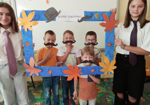 Uczennice trzymające ramkę do zdjęć oraz chłopcy z dekoracją.