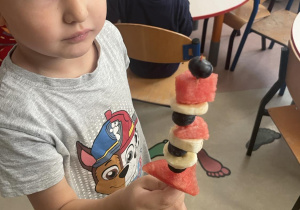 Chłopiec trzyma w ręku szaszłyka z arbuza banana i borówki