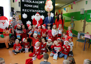 Wspólne zdjęcie przedszkolaków z grupy Pszczółki ze MIKOŁAJEM z panią dyrektor, panem wójtem oraz z wychowawcą. Śpiewanie piosenki dla Mikołaja.