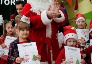 Zadowolone przedszkolaki trzymają w ręku dyplomy i nagrody.