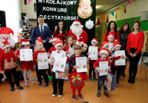 Pamiątkowe zdjęcie wszystkich uczestników Mikołajkowego Konkursu Recytatorskiego z Mikołajem, Panią Dyrektor, Panem Wójtem , koordynatorem konkursu i jury.