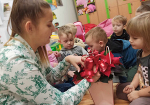 Pani Justyna dekoruje koszyk kokardą