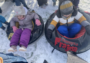 Chłopiec i dziewczynka siedzą w pontonach zimowych.