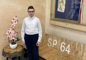 Kacper Jadczak pod sztandarem Szkoły Podstawowej nr 64 w Łodzi, w której odbyło się podsumowanie konkursu,