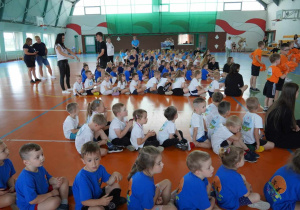 Dzieci siedzą w grupach podczas otwarcia Olimpiady