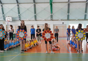 Dzieci siedzą w grupach podczas otwarcia Olimpiady