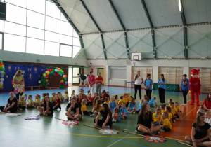 Dzieci siedzą w grupach podczas otwarcia Olimpiady