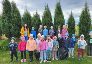 Grupa sprzątających przedszkolaków na boisku szkolnym