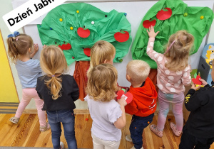 Chłopcy i dziewczynki naklejają jabłka na drzewach