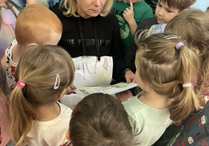 Pani nauczycielka ogląda rysunki namalowane przez dzieci i słuch tworzonych przez dzieci legend.