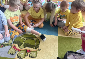 Próby zawijania rany bandażem przez dzieci z grupy Biedronki i Motylki.