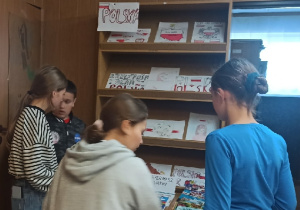 Uczniowie SP w Rzeczycy oglądają książki w czasie Kiermaszu Książki w bibliotece szkolnej.