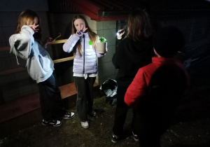 Zadowolone uczennice po wykonaniu zadania podczas podchodów. Jedna z uczennic trzyma w ręku posadzoną roślinę w doniczce.