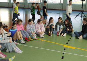 Dzieci siedzą na podłodze i pokazują dwie różne kolorowe skarpetki.