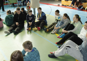 Dzieci siedzą na podłodze i pokazują dwie różne kolorowe skarpetki.