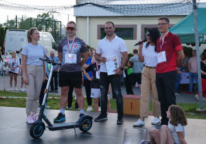 Zwycięzca hulajnogi elektrycznej odbiera swoją wygraną.