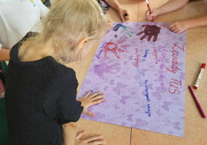 Uczennice podpisują się na plakacie.