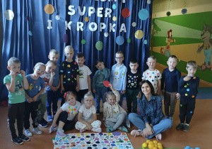 Zdjęcie grupowe dzieci z grupy Promyczki na tle napisu Jestem super i kropka.