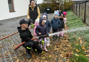 Dziewczynka z grupy Żabki próbuje swoich sił przy obsłudze węża gaśniczego.