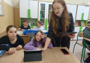 Pani prowadząca przedstawia uczennicom możliwości programowania robotów.