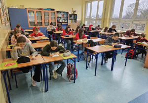 Uczniowie siedzą w ławkach i rozwiązują test wstępny.