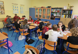 Uczniowie siedzą w trzech grupach.
