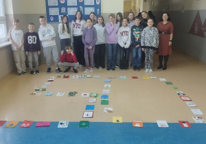 Uczniowie klasy 5 oraz Pani Marta Skoneczny i Pani Marta Płocka stoją za liczbą 50 ułożoną na podłodze z otrzymanych kartek świątecznych.