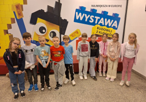 Grupa pierwszoklasistów przed wystawą z klocków Lego.