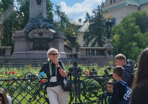 Uczniowie słuchają przewodnika, w tle pomnik Adama Mickiewicza.