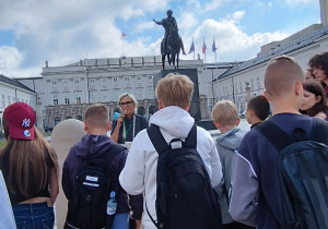 Uczniowie słuchają przewodnika, w tle Pałac Prezydencki.