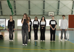 Grupa uczniów z klasy VIII przedstawia scenkę „Pół wieku w szkolnym dzwonku”.