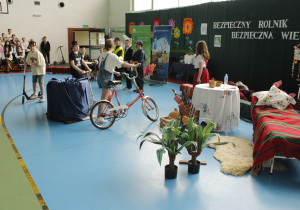Grupa uczniów jadących na hulajnogach i rowerze.