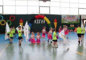 Dziewczynki z grupy "Żabki" w strojach cheerleaderek biegają po kole.