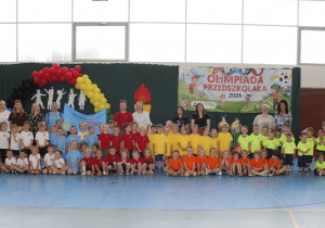 Zdjęcie grupowe ośmiu drużyn na tle dekoracji w kategorii 3-4 lat.