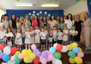 Dzieci z grupy Słoneczka z dyplomami podczas zakończenia roku przedszkolnego wraz z rodzicami i kadrą pedagogiczną.