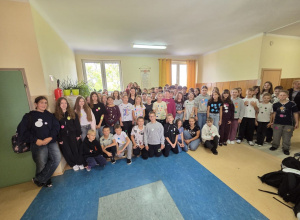 Uczniowie klas 4 – 8 na korytarzu szkolnym prezentują swoje ubrania w kropki.