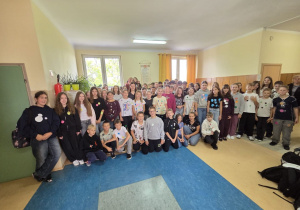 Uczniowie klas 4 – 8 na korytarzu szkolnym prezentują swoje ubrania w kropki.