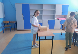 Uczennica klasy 4 wkłada kartę do głosowania do skrzynki.
