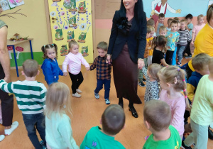 Przedszkolaki tańczące w kole z Panią Dyrektor.