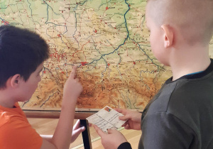 Kacper Heleniak i Kacper Kania poszukują na mapie Polski miejscowości , z których klasa otrzymała pocztówki.