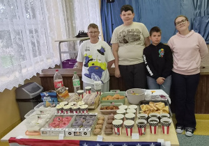 Uczniowie 6 klasy przy stoisku z amerykańskimi przekąskami i flagą USA.