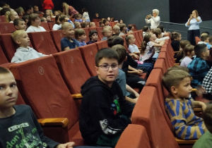Chłopcy i dziewczynki oglądające przedstawienie teatralne.