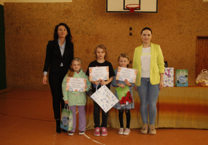 na zdjęciu widać dwie dorosłe kobiety i trójka dzieci z dyplomami i nagrodami w ręku.