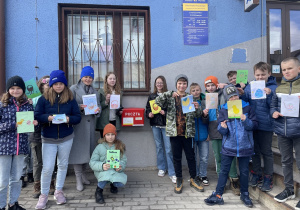 Zadowoleni uczniowie przed Urzędem Poczty Polskiej w Rzeczycy wysyłają karty wielkanocne.