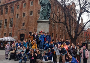 Zadowoleni uczniowie przed pomnikiem Mikołaja Kopernika