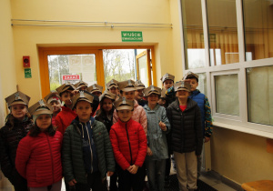 Uczniowie w czapkach zrobionych podczas wizyty w muzeum